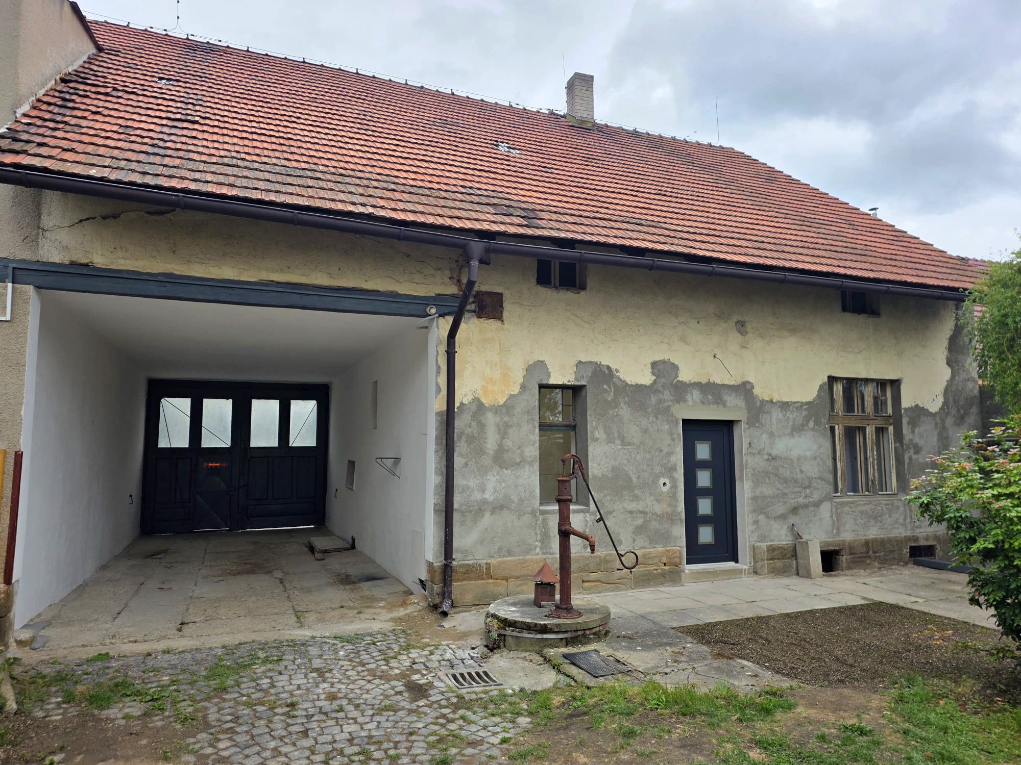 Dvorní strana domu s krytým vjezdem a historickou pumpou